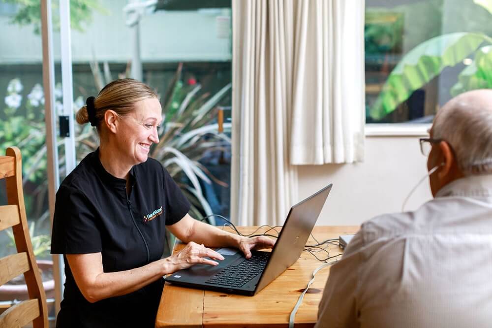 Jennifer Abbott of Hear At Home Mobile Hearing Clinic North Vancouver with an assisted listening device connected to a laptop